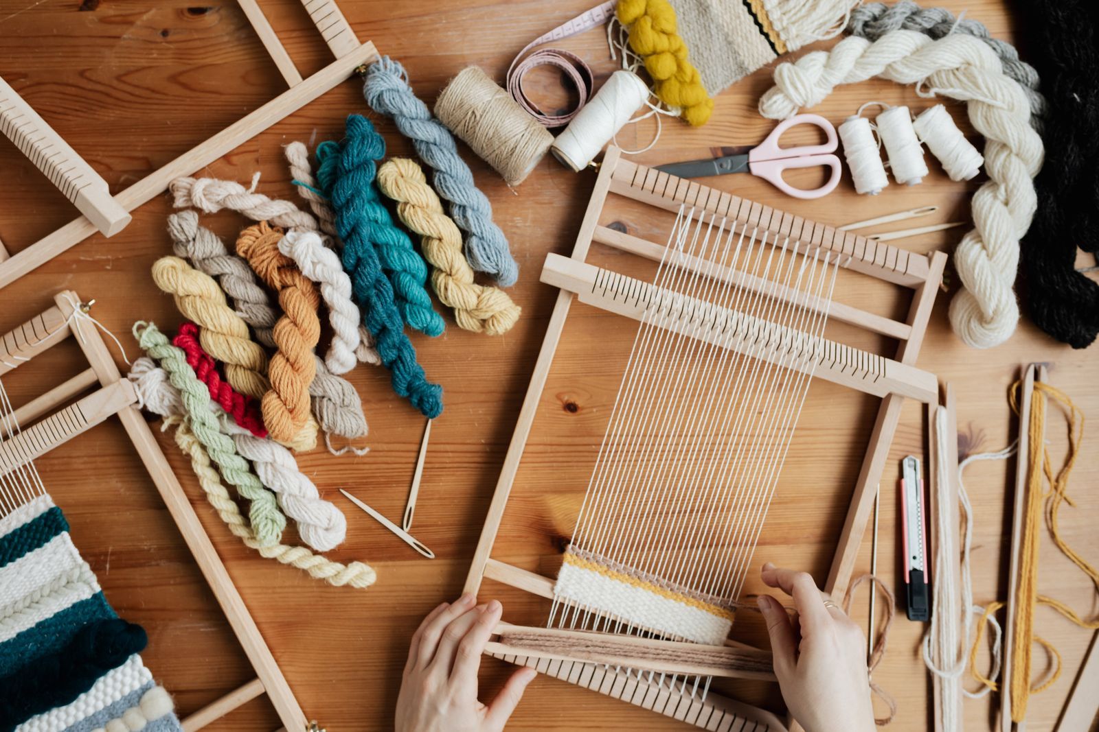 Hands weaving colourful yarn on a loom